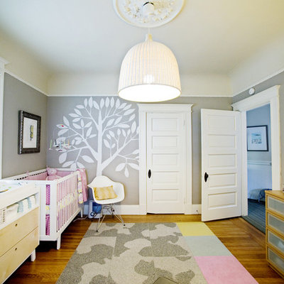 Example of a mid-sized transitional girl medium tone wood floor nursery design in San Francisco with gray walls