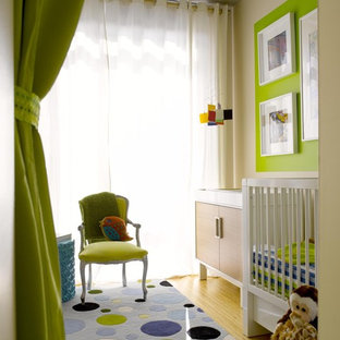 Immagine di una piccola cameretta per neonati neutra minimal con pareti verdi e pavimento in bambù