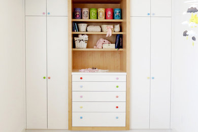 Ejemplo de habitación de bebé niña actual pequeña con paredes blancas y suelo de madera clara