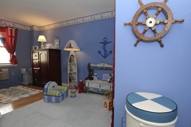 Imagen de habitación de bebé niño bohemia de tamaño medio con paredes azules y suelo de madera en tonos medios