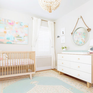 Imagen de habitación de bebé niña tradicional renovada, pequeña, con paredes beige y suelo de madera clara