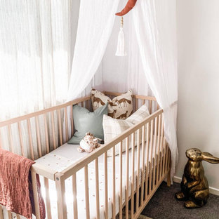 Imagen de habitación de bebé neutra contemporánea con paredes blancas, moqueta y suelo gris