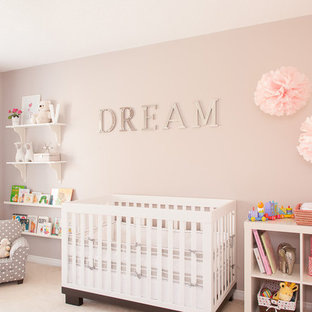 Modelo de habitación de bebé niña tradicional renovada con paredes rosas, moqueta y suelo beige