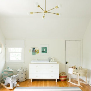 Example of a mid-sized eclectic gender-neutral medium tone wood floor and brown floor nursery design in Nashville with white walls