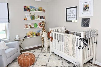 Ejemplo de habitación de bebé neutra moderna con paredes grises, suelo de madera oscura y suelo marrón