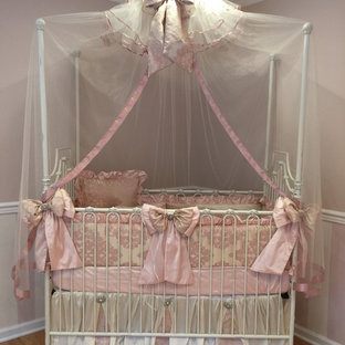 Ejemplo de habitación de bebé niña clásica, grande, con paredes rosas y suelo de madera clara