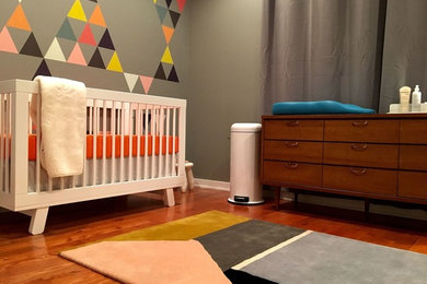 Idée de décoration pour une chambre de bébé garçon minimaliste de taille moyenne avec un mur gris, un sol en bois brun et un sol marron.