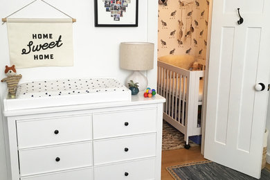 Imagen de habitación de bebé contemporánea pequeña con paredes blancas y suelo de madera clara