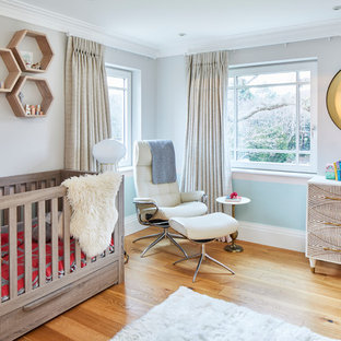 Photo of a large contemporary nursery in Surrey with blue walls and medium hardwood flooring.