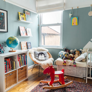 Scandi gender neutral nursery in Other with blue walls, light hardwood flooring and brown floors.