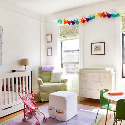 Nursery - large transitional girl medium tone wood floor nursery idea in New York with white walls