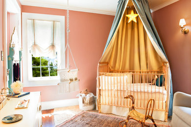 Cette image montre une chambre de bébé fille bohème de taille moyenne avec un mur rose, moquette et un sol beige.