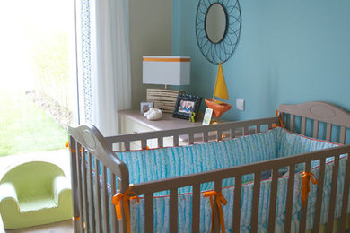 Cette photo montre une petite chambre de bébé neutre tendance avec un sol en bois brun.