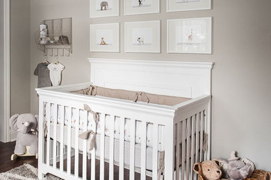 Modelo de habitación de bebé neutra clásica renovada de tamaño medio con paredes grises y suelo de madera oscura