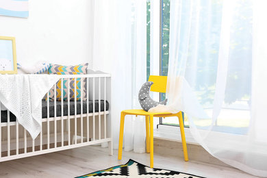 Modelo de habitación de bebé neutra minimalista de tamaño medio con paredes blancas y suelo de madera clara