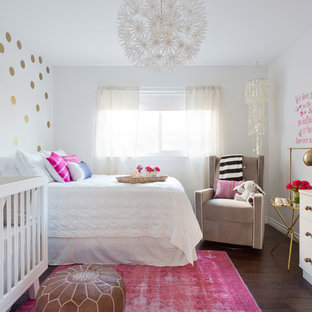 Ispirazione per una piccola cameretta per neonata boho chic con pareti bianche, pavimento in laminato e pavimento marrone