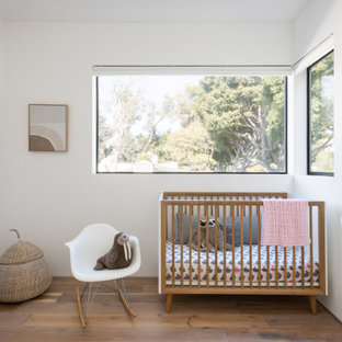 Inspiration for a small contemporary gender-neutral medium tone wood floor and brown floor nursery remodel in Los Angeles with white walls