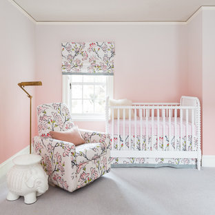 Immagine di una cameretta per neonata tradizionale con pareti rosa, moquette e pavimento grigio