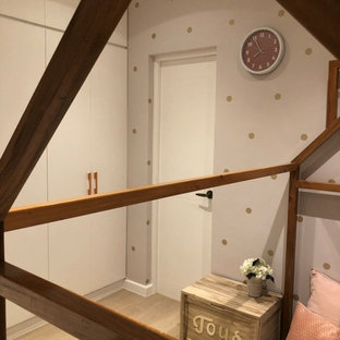 Foto di una grande cameretta per neonati neutra country con pareti rosa, pavimento in laminato e pavimento marrone