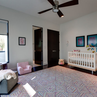 Example of a large trendy gender-neutral dark wood floor nursery design in Houston with white walls