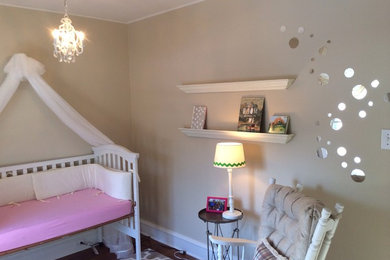 Imagen de habitación de bebé neutra tradicional renovada de tamaño medio con paredes beige y suelo de madera en tonos medios