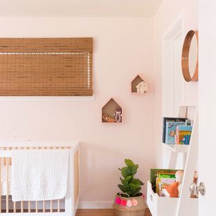 Esempio di una piccola cameretta per neonata bohémian con pareti rosa, parquet chiaro e pavimento giallo