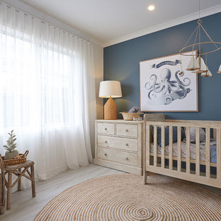 This is an example of a beach style nursery for boys in Melbourne with white walls, light hardwood floors and beige floor.