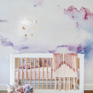 Ejemplo de habitación de bebé niña tradicional renovada, de tamaño medio, con paredes multicolor y suelo de madera en tonos medios