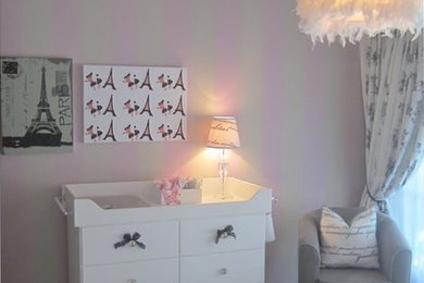 Modelo de habitación de bebé niña tradicional renovada de tamaño medio con paredes rosas y suelo de madera clara