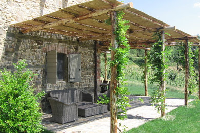 Foto di un grande patio o portico country davanti casa con pavimentazioni in pietra naturale e una pergola