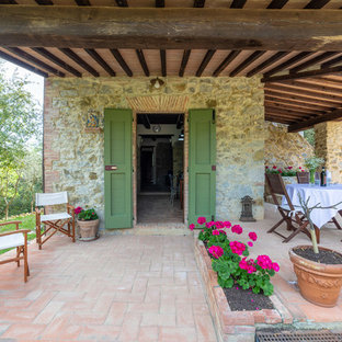 Foto di un patio o portico country dietro casa con piastrelle e un tetto a sbalzo