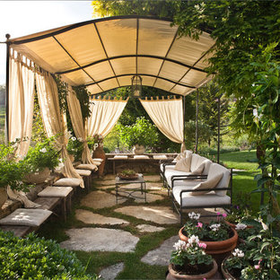 Ispirazione per un grande patio o portico country con pavimentazioni in pietra naturale, un giardino in vaso e un parasole