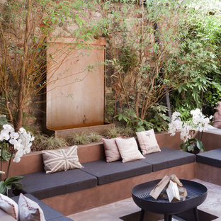 Immagine di un patio o portico bohémian dietro casa con un focolare, lastre di cemento e nessuna copertura