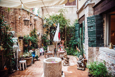 Inspiration for a country courtyard patio in Venice with brick paving and an awning.
