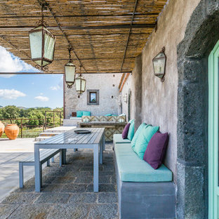 Foto di un patio o portico mediterraneo dietro casa con lastre di cemento e un parasole