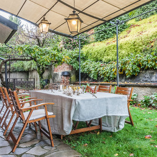 Ispirazione per un patio o portico chic dietro casa con pavimentazioni in pietra naturale e un parasole