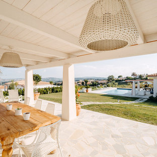 Immagine di un patio o portico mediterraneo dietro casa con piastrelle e un tetto a sbalzo