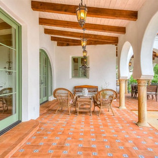 Immagine di un grande patio o portico mediterraneo dietro casa con piastrelle e un tetto a sbalzo