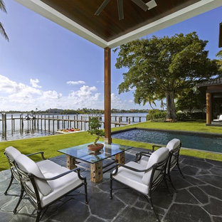 Immagine di un ampio patio o portico etnico dietro casa con pavimentazioni in pietra naturale e un tetto a sbalzo