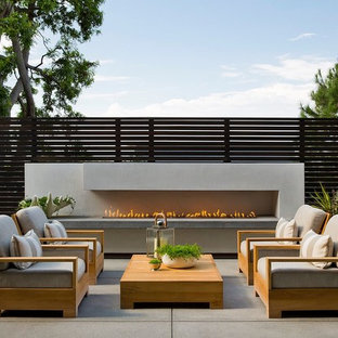 Photo of a contemporary patio in Los Angeles with concrete slabs, no cover and a fireplace.