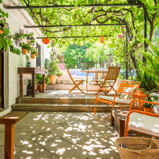 Foto di un grande patio o portico country dietro casa con piastrelle e una pergola
