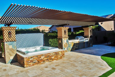 Exemple d'une terrasse arrière chic de taille moyenne avec une cuisine d'été, des pavés en brique et une pergola.