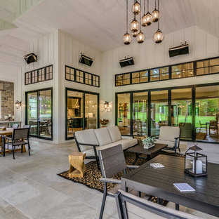 Immagine di un grande patio o portico country dietro casa con un tetto a sbalzo e pavimentazioni in pietra naturale