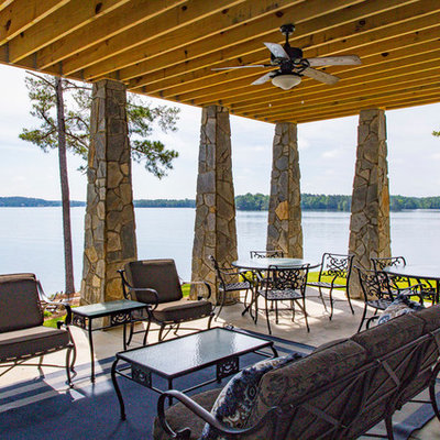 Example of a mountain style backyard concrete patio design in Other with a roof extension