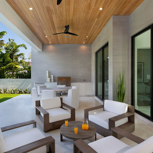 Large modern back patio in Miami with an outdoor kitchen, stamped concrete and a roof extension.