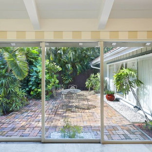 Ispirazione per un patio o portico tropicale di medie dimensioni e dietro casa con pedane e un tetto a sbalzo