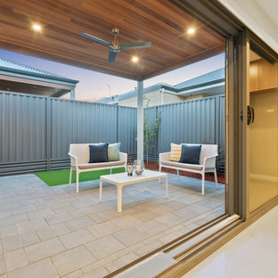 Immagine di un piccolo patio o portico moderno dietro casa con pavimentazioni in mattoni e un tetto a sbalzo