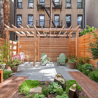 Small trendy backyard stone patio photo in New York with a pergola
