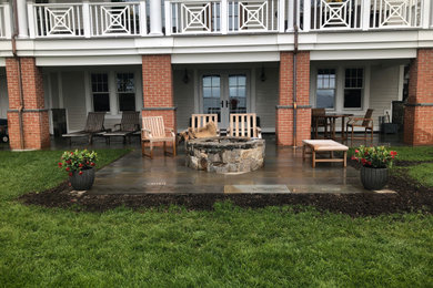 Example of a trendy backyard stone patio design with a fire pit