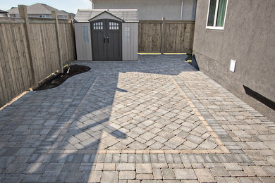 Example of a mid-sized transitional backyard concrete paver patio design in Other